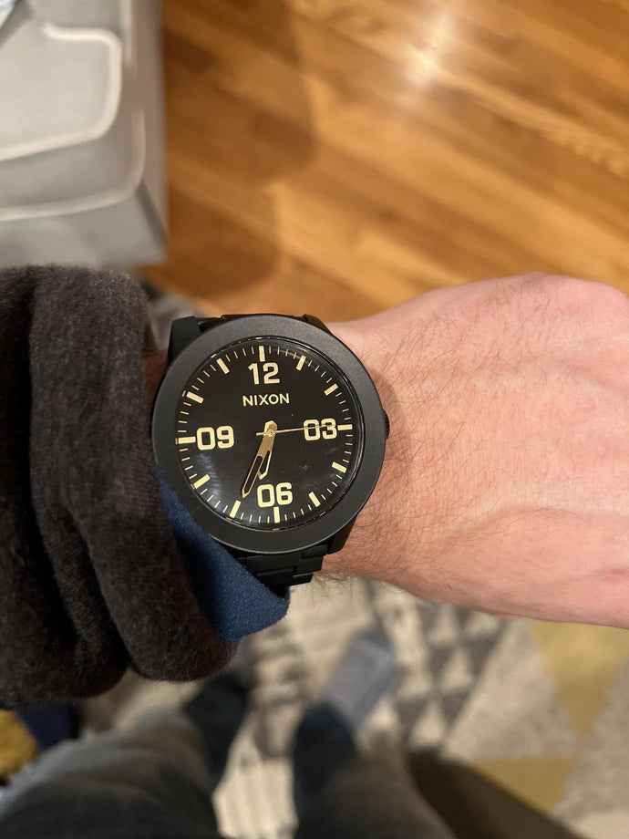 Man wearing a black and gold Nixon Corporal watch
