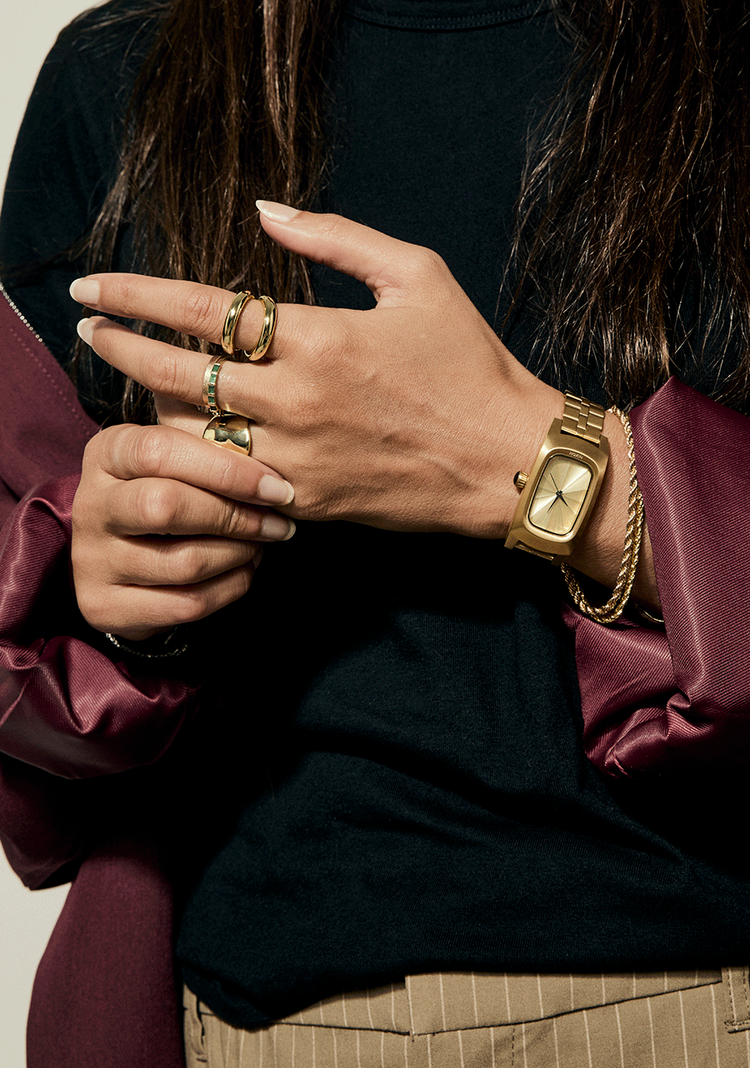 Women's wrist wearing a gold Nixon Frankie watch