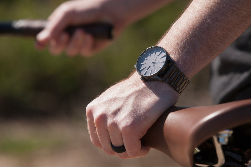 Person wearing a Nixon analog watch getting ready to ride a bike